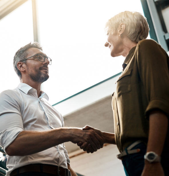 A professional handshake between a man and woman in an office