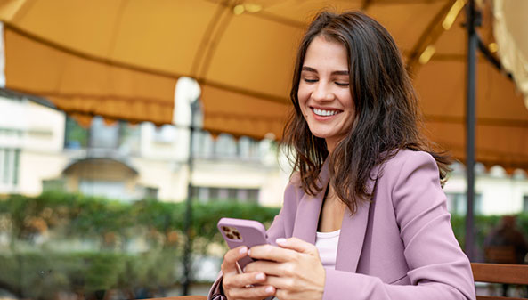 A woman smiles while holding her cell phone